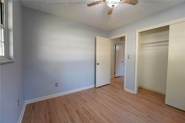 unfurnished bedroom with ceiling fan, a textured ceiling, light wood-type flooring, and a closet