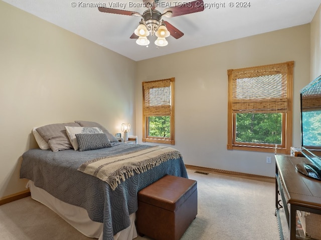 carpeted bedroom featuring multiple windows and ceiling fan