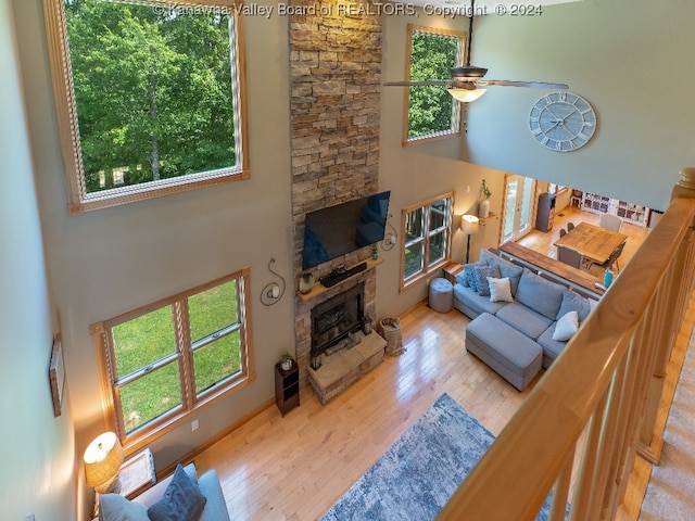 living room featuring a fireplace, hardwood / wood-style flooring, ceiling fan, and a towering ceiling