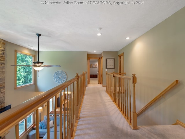 hall featuring a textured ceiling and light carpet