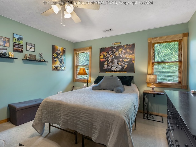 carpeted bedroom featuring a textured ceiling, multiple windows, and ceiling fan