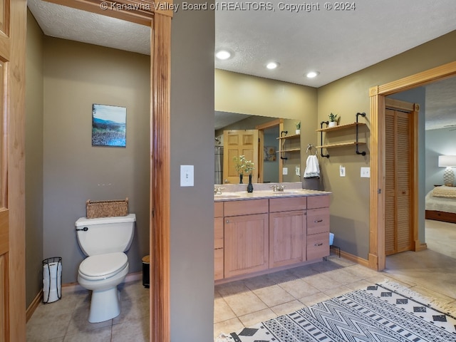 bathroom with toilet, vanity, a textured ceiling, and tile patterned floors