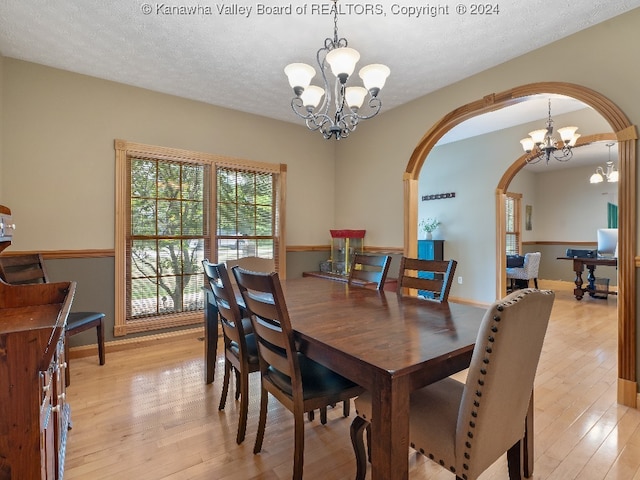 dining room featuring an inviting chandelier, a textured ceiling, and light hardwood / wood-style floors