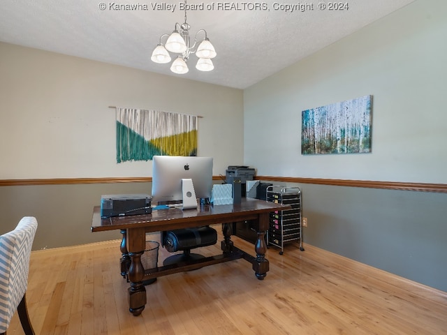 home office with light hardwood / wood-style floors, a textured ceiling, and a notable chandelier