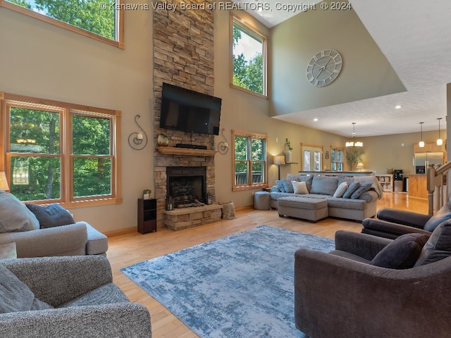 living room with light hardwood / wood-style floors, a healthy amount of sunlight, a textured ceiling, and a towering ceiling