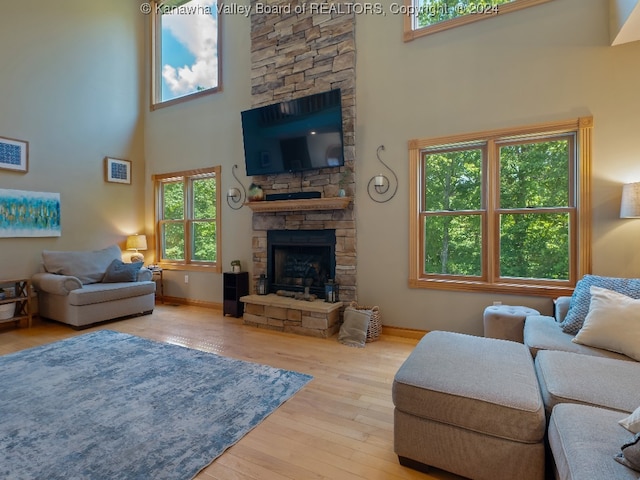 living room featuring a towering ceiling, light hardwood / wood-style floors, and a fireplace