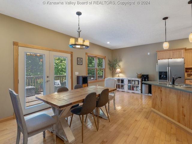 dining space with sink, light hardwood / wood-style flooring, french doors, and a notable chandelier