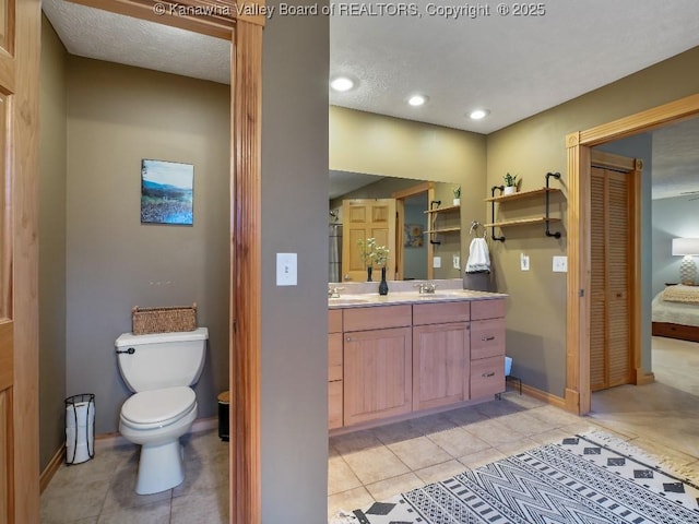 bathroom featuring tile patterned floors, a textured ceiling, vanity, and toilet