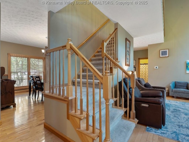 stairway featuring an inviting chandelier, hardwood / wood-style flooring, and a textured ceiling