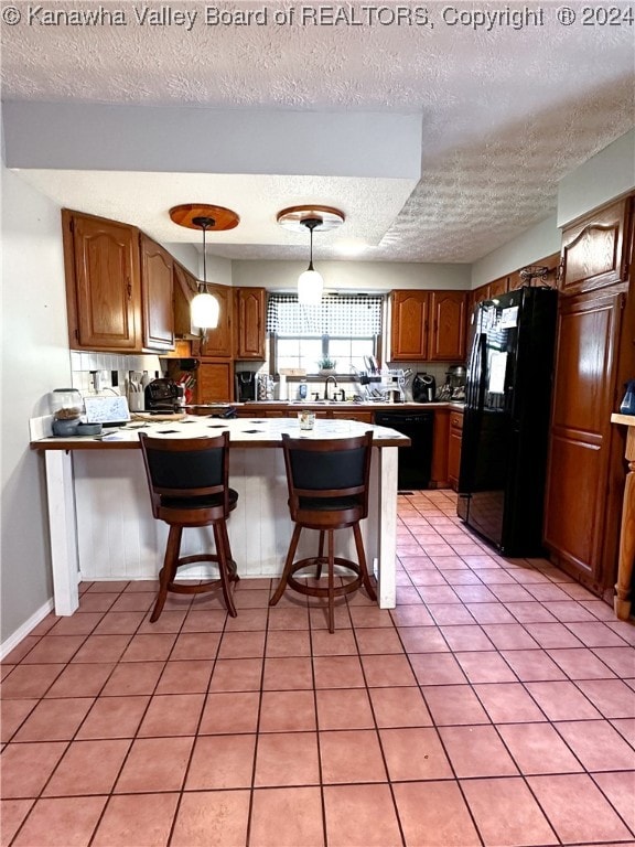 kitchen featuring a kitchen breakfast bar, decorative light fixtures, kitchen peninsula, black appliances, and a textured ceiling