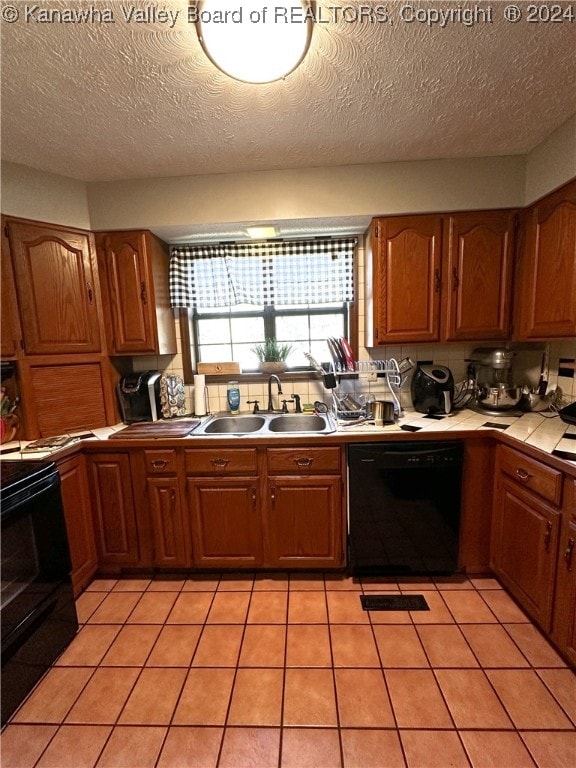 kitchen with black appliances, sink, light tile patterned floors, and a textured ceiling