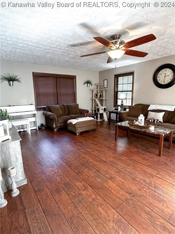 living room featuring ceiling fan, a textured ceiling, and dark hardwood / wood-style flooring