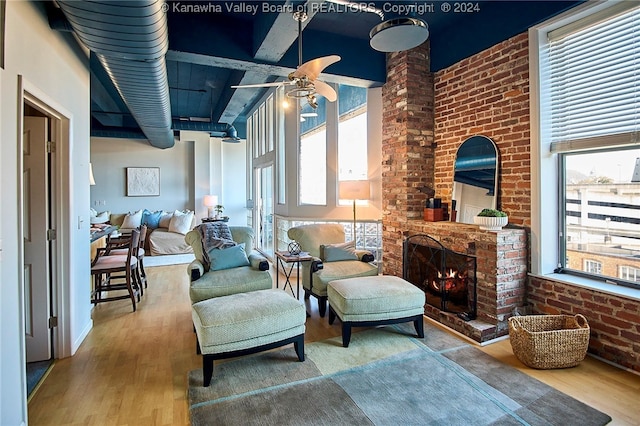 sitting room with brick wall, hardwood / wood-style flooring, and plenty of natural light