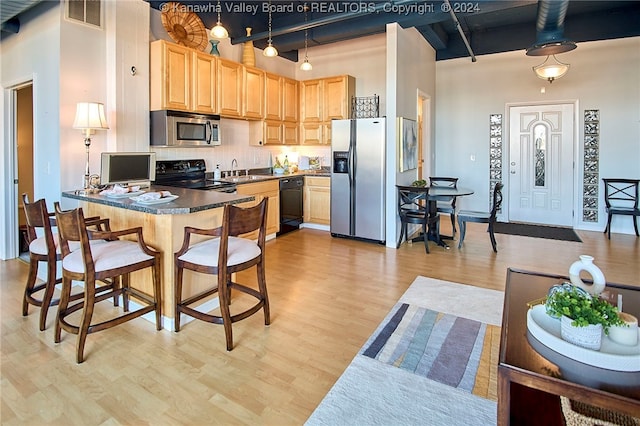 kitchen featuring sink, kitchen peninsula, black appliances, light brown cabinetry, and light wood-type flooring