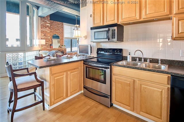 kitchen with stainless steel appliances, sink, light hardwood / wood-style floors, kitchen peninsula, and a breakfast bar area