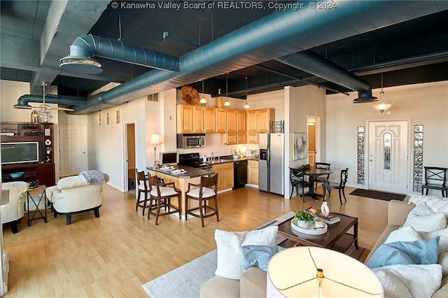 living room featuring a towering ceiling, light hardwood / wood-style floors, and sink