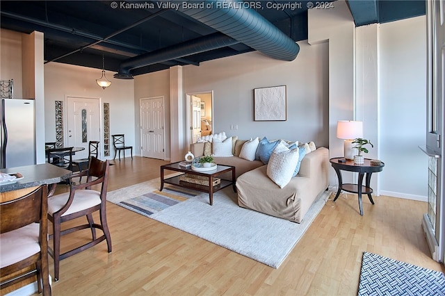 living room featuring a towering ceiling and light hardwood / wood-style floors