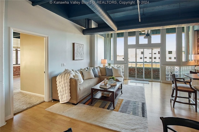 living room featuring a towering ceiling, plenty of natural light, and light hardwood / wood-style floors