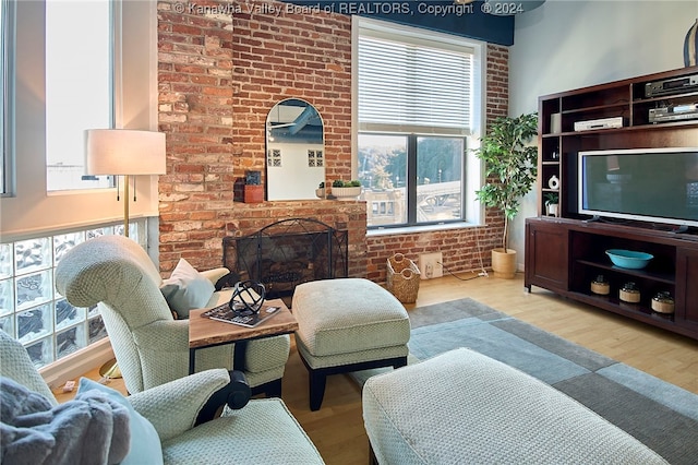 living room with a brick fireplace, light hardwood / wood-style floors, and brick wall