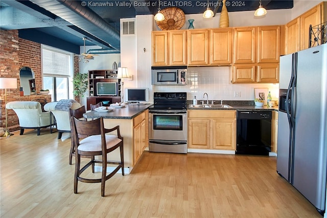 kitchen with stainless steel appliances, pendant lighting, sink, and light wood-type flooring