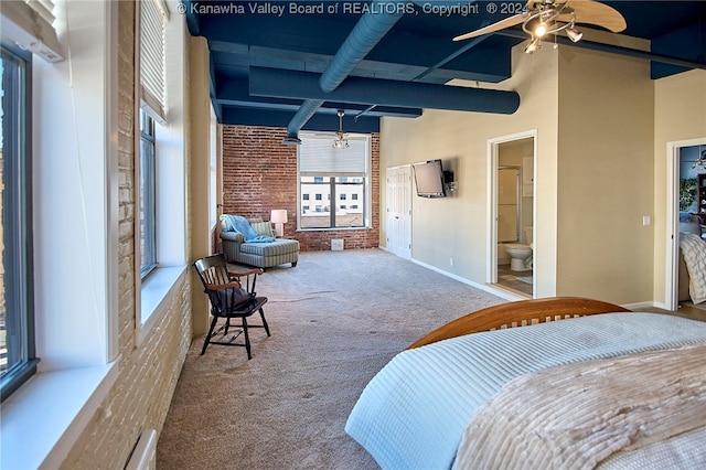 carpeted bedroom with brick wall, a high ceiling, connected bathroom, and ceiling fan