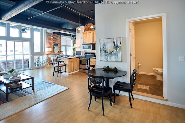 dining space with a high ceiling, ceiling fan, and light hardwood / wood-style flooring