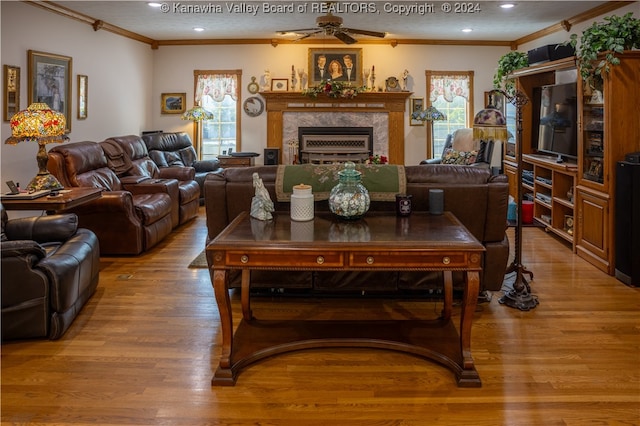 living room with ceiling fan, light hardwood / wood-style flooring, a fireplace, and ornamental molding