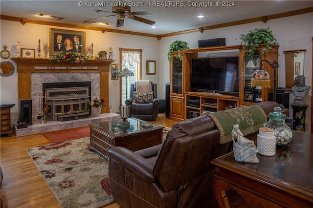 living room featuring a textured ceiling, crown molding, light wood-type flooring, and ceiling fan