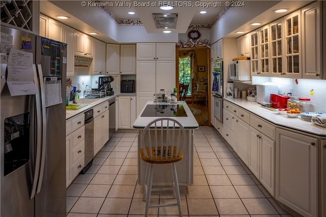 kitchen featuring light tile patterned floors, stainless steel appliances, white cabinetry, and a center island