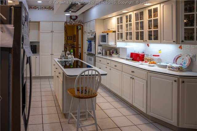 kitchen featuring light tile patterned flooring, white appliances, a center island, and white cabinets