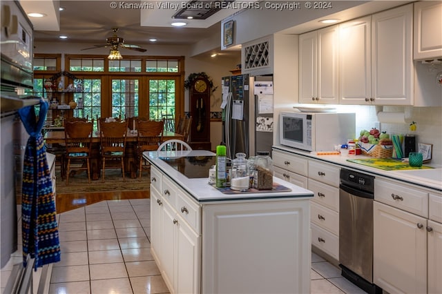 kitchen with light tile patterned flooring, stainless steel refrigerator with ice dispenser, a kitchen island, and white cabinetry