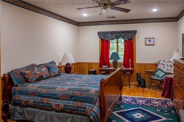 bedroom featuring ceiling fan, a textured ceiling, light wood-type flooring, and wooden walls