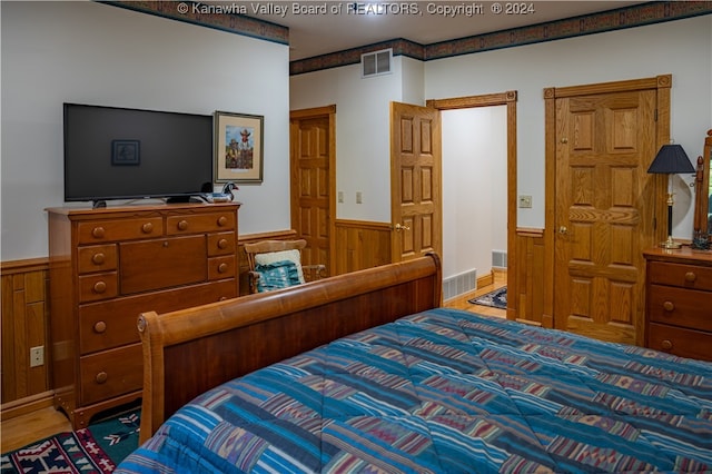 bedroom featuring wooden walls and hardwood / wood-style floors