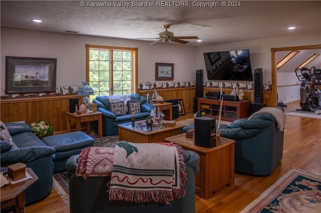 living room with hardwood / wood-style flooring, ceiling fan, and a textured ceiling