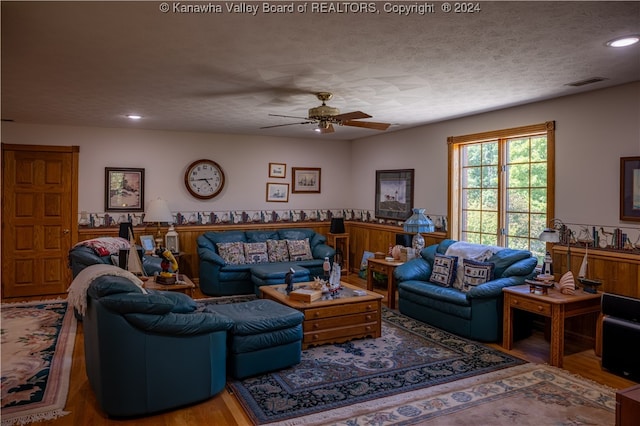 living room featuring wood-type flooring, a textured ceiling, and ceiling fan