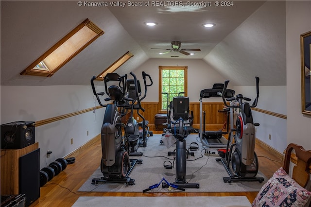 exercise room with ceiling fan, light hardwood / wood-style flooring, and lofted ceiling with skylight