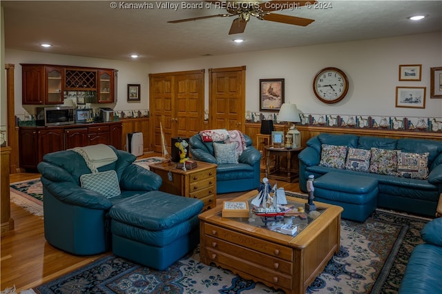 living room featuring ceiling fan, wood-type flooring, and a textured ceiling