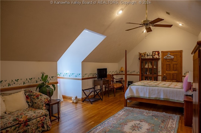 bedroom featuring ceiling fan, hardwood / wood-style floors, and lofted ceiling with skylight