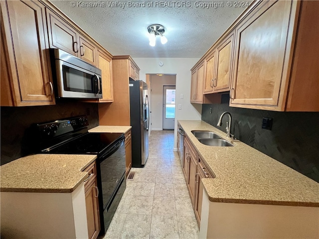 kitchen featuring sink, light stone countertops, stainless steel appliances, and a textured ceiling