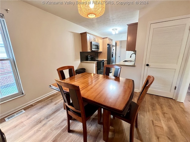 dining area with a textured ceiling, sink, and light wood-type flooring