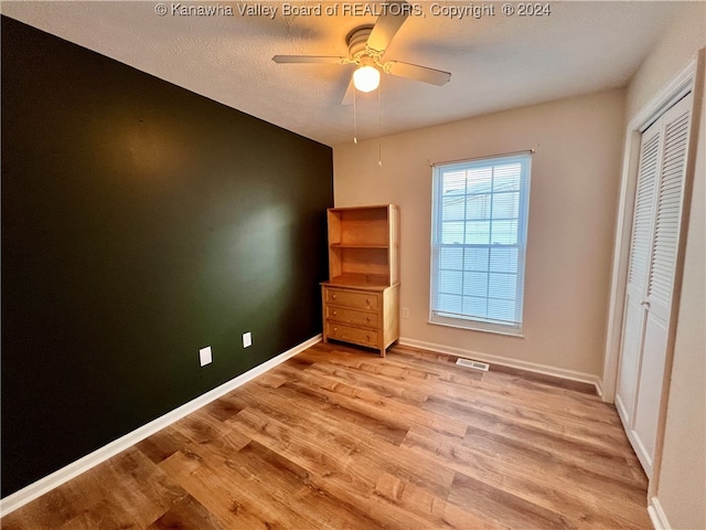 unfurnished bedroom featuring a closet, ceiling fan, a textured ceiling, and light hardwood / wood-style floors