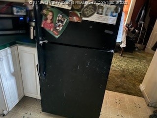 room details featuring white cabinetry and black refrigerator