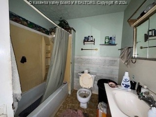 full bathroom with tile walls, shower / bathtub combination with curtain, vanity, and toilet