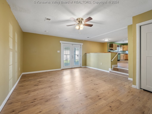 spare room with french doors, a textured ceiling, light wood-type flooring, and ceiling fan