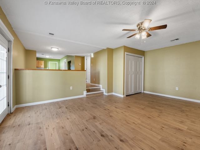 empty room with light hardwood / wood-style floors, a textured ceiling, and ceiling fan