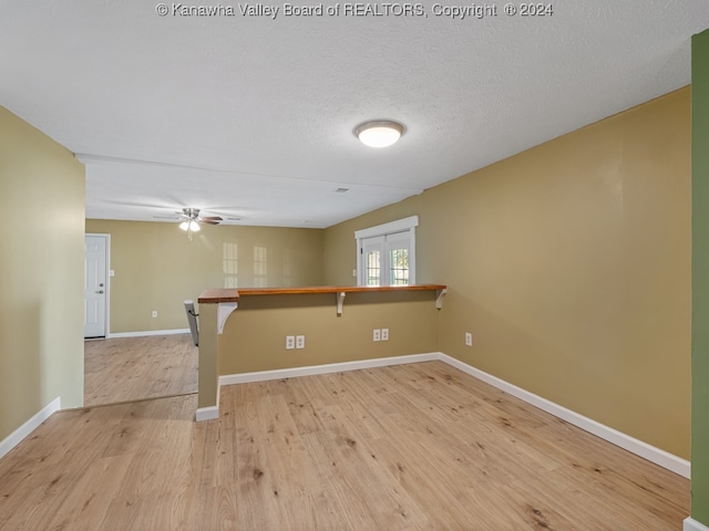 unfurnished room featuring light hardwood / wood-style floors, french doors, a textured ceiling, and ceiling fan