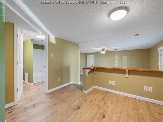 unfurnished room with light hardwood / wood-style flooring, a textured ceiling, and ceiling fan