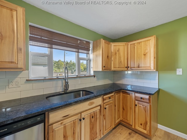 kitchen with dishwasher, light hardwood / wood-style flooring, dark stone counters, sink, and tasteful backsplash