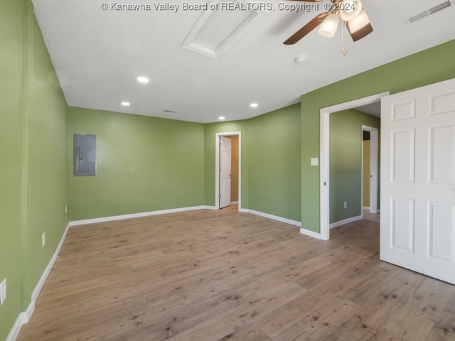 empty room with electric panel, light wood-type flooring, and ceiling fan