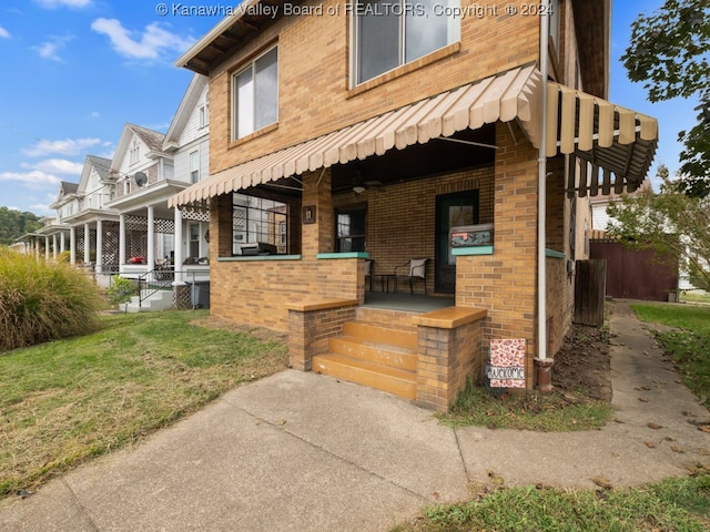 view of side of home featuring covered porch and a lawn